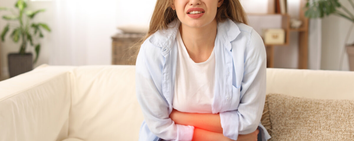 Young woman suffering from menstrual cramps at home