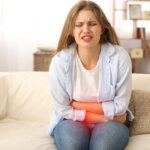 Young woman suffering from menstrual cramps at home