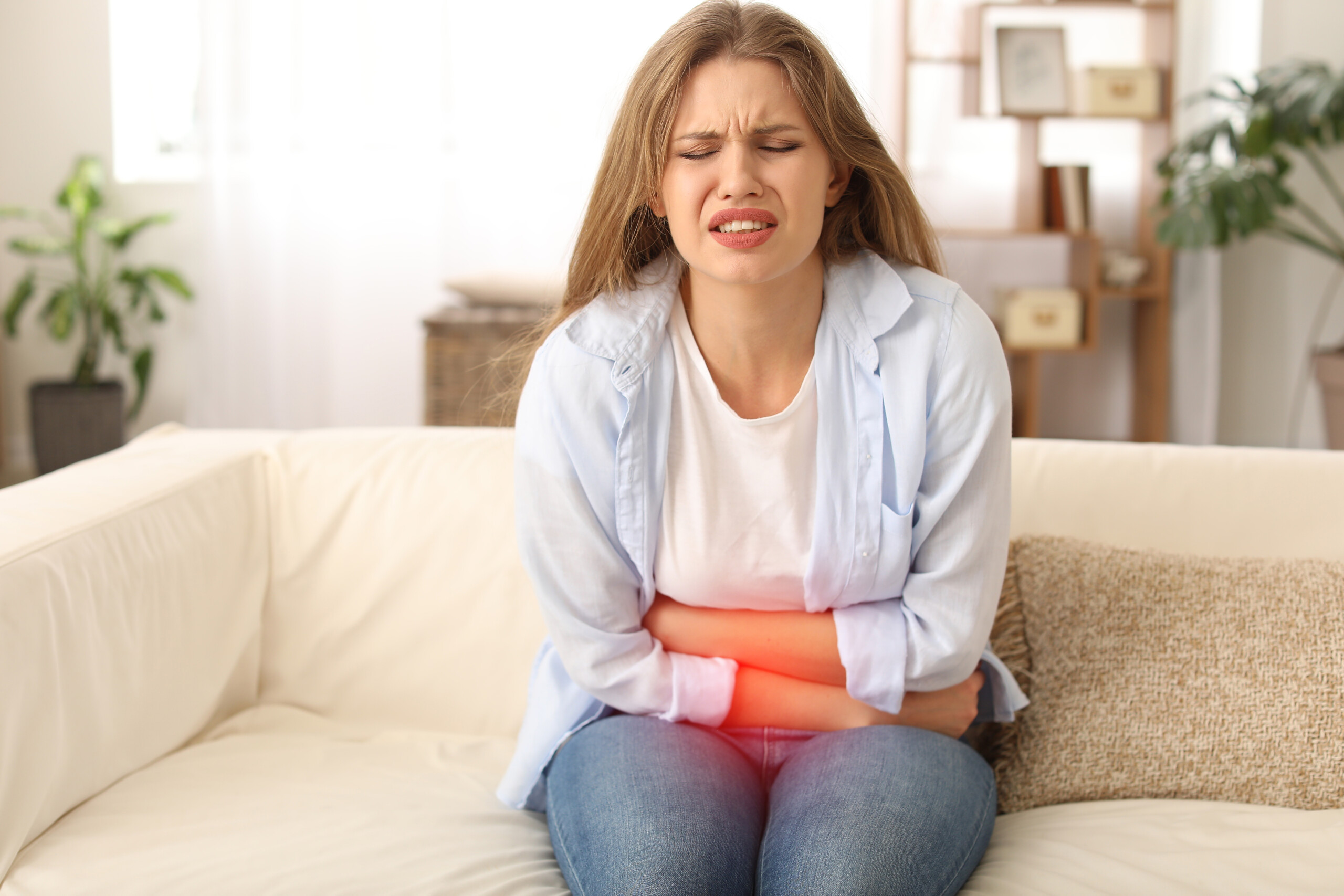 Young woman suffering from menstrual cramps at home